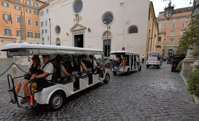 A flotilla of golf carts carrying tourists travels past the Basilica of Santa Maria sopra Minerva in Rome, Thursday, Aug. 27, 2026, as city officials move to regulate the rapidly growing industry amid complaints about congestion, illegal parking, and overtourism. (AP Photo/Gregorio Borgia)