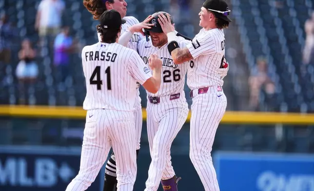 Colorado Rockies' Brett Sullivan, back center, is congratulated after his walkoff RBI single by teammates Nick Frasso, front, Zac Veen, back left, and Cole Carrigg in the 11th inning of a baseball game against the Baltimore Orioles Wednesday, Sept. 2, 2026, in Denver. (AP Photo/David Zalubowski)