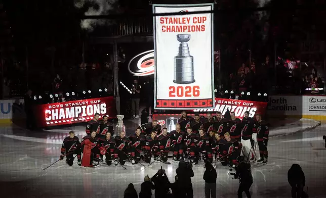 Carolina Hurricanes pose for a group photo as the championship banner is raised during the team's Stanley Cup celebration before their season-opening NHL hockey game against the Florida Panthers in Raleigh, N.C., Tuesday, Sept. 29, 2026. (AP Photo/Karl DeBlaker)