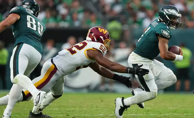Philadelphia Eagles quarterback Jalen Hurts (1) runs from Washington Commanders linebacker Sonny Styles (52) during the second half of an NFL football game, Sunday, Sept. 13, 2026, in Philadelphia. (AP Photo/Matt Rourke)