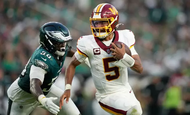 Washington Commanders quarterback Jayden Daniels (5) scramble past Philadelphia Eagles linebacker Keyshawn James-Newby (50) during the second half of an NFL football game, Sunday, Sept. 13, 2026, in Philadelphia. (AP Photo/Matt Slocum)