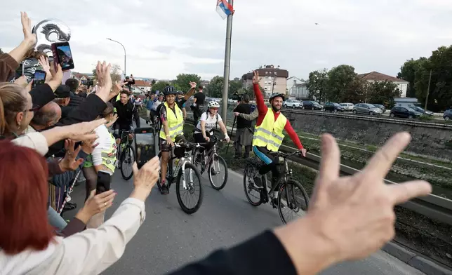 People welcome a group of university students at the end of their cycling tour of the Balkan country ahead of an early election next month challenging populist President Aleksandar Vucic, in Kragujevac, Serbia, Saturday, Sept. 26, 2026. (AP Photo/Marko Drobnjakovic)