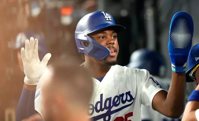 Los Angeles Dodgers' Josue De Paula is congratulated by teammates in the dugout after scoring on a walk by Mookie Betts during the second inning of a baseball game against the San Diego Padres, Tuesday, Sept. 22, 2026, in Los Angeles. (AP Photo/Mark J. Terrill)