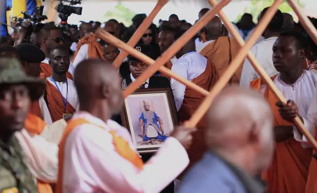 A Ugandan security officer carries a portrait of Tooro's King Oyo Nyimba during his funeral procession in Fort Portal, Uganda, Saturday, Sept. 12, 2026. (AP Photo/Patrick Onen)