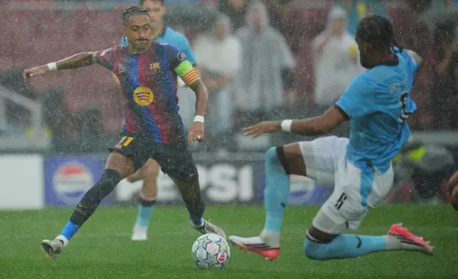 Barcelona's Raphinha dribbles past Feyenoord's Jerry St. Juste before scoring his team's opening goal during the Champions League opening phase soccer between Barcelona and Feyenoord in Barcelona, Spain, Wednesday, Sept. 9, 2026.(AP Photo/Emilio Morenatti)
