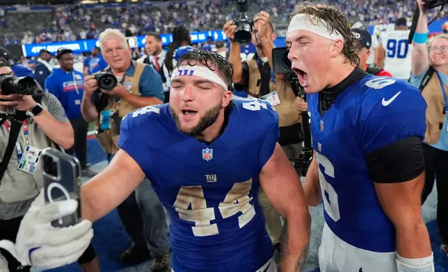 New York Giants running back Cam Skattebo (44) and quarterback Jaxson Dart (6) react with a cell phone following an NFL football game against the Dallas Cowboys Sunday, Sept. 13, 2026, in East Rutherford, N.J. (AP Photo/Yuki Iwamura)