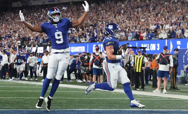 New York Giants running back Cam Skattebo, right, with teammate Isaiah Likely (9) celebrating, scores a touchdown against the Dallas Cowboys during the first half of an NFL football game Sunday, Sept. 13, 2026, in East Rutherford, N.J. (AP Photo/Pamela Smith)