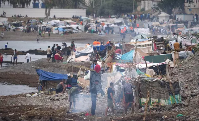 Migrants stand near their tents at El Trampolín beach in the Spanish exclave of Ceuta, Wednesday, Sept. 2, 2026. (AP Photo/Francis González)