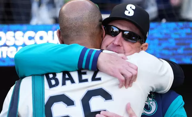 Seattle Mariners manager Dan Wilson, facing, greets bullpen catcher Fleming Báez (66) after a win over the Los Angeles Angels in a baseball game, Sunday, Sept. 27, 2026, in Seattle. (AP Photo/Lindsey Wasson)