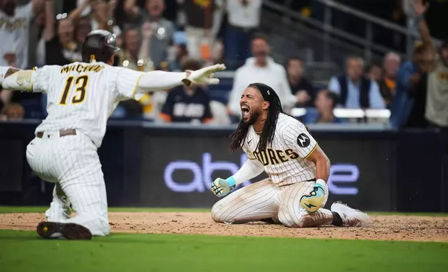 San Diego Padres Fernando Tatis Jr. reacts with third baseman Manny Machado (13) after scoring on a steal and an error by Chicago Cubs in the seventh inning of Game 1 of the National League Wild Card baseball playoff series Tuesday, Sept. 29, 2026, in San Diego. (AP Photo/Gregory Bull)