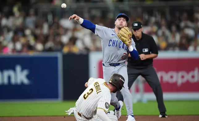 Chicago Cubs second baseman Nico Hoerner (2) turns a double play on San Diego Padres center fielder Jackson Merrill (3) in the fourth inning of Game 1 of the National League Wild Card baseball playoff series Tuesday, Sept. 29, 2026, in San Diego. (AP Photo/Gregory Bull)
