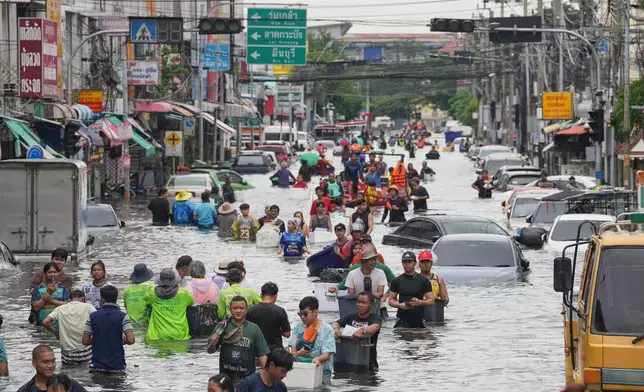 People wade through a flooded street after heavy rain in Bangkok, Thailand, Monday, Sept. 28, 2026. (AP Photo/Sakchai Lalit)