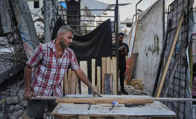 Palestinian carpenter Alaa Joudah, 39, cuts wood to use for building a new wooden house next to his home, which was destroyed during the war between Israel and Hamas, in Gaza City, Wednesday, Sept. 2, 2026. (AP Photo/Abdel Kareem Hana)