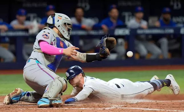 Tampa Bay Rays' Taylor Walls scores ahead of the throw to New York Mets catcher Francisco Alvarez on an RBI single by Liam Hicks during the eighth inning of a baseball game Monday, Aug. 31, 2026, in St. Petersburg, Fla. (AP Photo/Chris O'Meara)