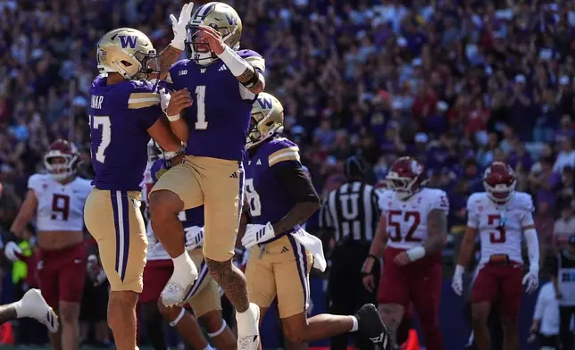 Washington quarterback Demond Williams Jr. (1) jumps to celebrate scoring a touchdown with running back Jayden Limar (17) during the first half of an NCAA college football game against Washington State, Sunday, Sept. 6, 2026, in Seattle. (AP Photo/Lindsey Wasson)