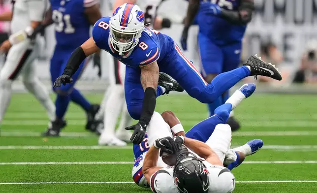 Buffalo Bills linebacker Terrel Bernard (8) jumps to avoid Houston Texans tight end Foster Moreau, below right, who is tackled by cornerback Davison Igbinosun (21) during the second half of an NFL football game, Sunday, Sept. 13, 2026, in Houston. (AP Photo/Ashley Landis)