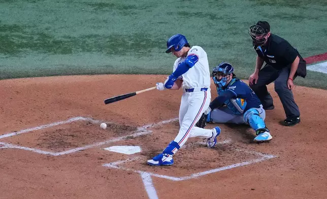 Texas Rangers' Justin Foscue connects for an RBI single to score teammate Wyatt Langford as Tampa Bay Rays catcher Nick Fortes, center, and home plate umpire Lance Barksdale (23) look on during the fourth inning of a baseball game Thursday, Sept. 3, 2026, in Arlington, Texas. (AP Photo/Julio Cortez)