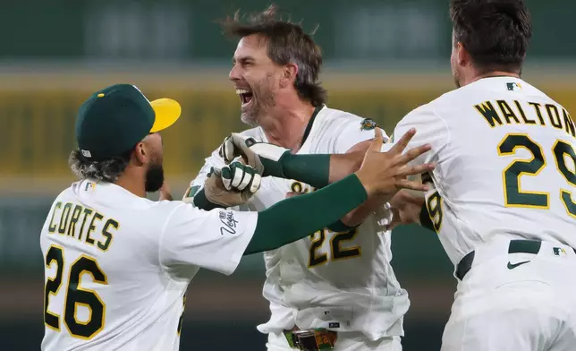 Athletics' Jeff McNeil, middle, is mobbed by his teammates after hitting a walk off RBI single during the ninth inning of a baseball game against the Toronto Blue Jays Monday, Sept. 7, 2026, in West Sacramento, Calif. (AP Photo/Scott Marshall)