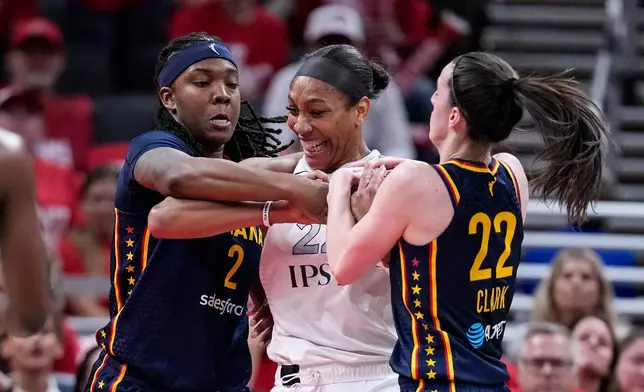 Indiana Fever guard Caitlin Clark (22) and forward Myisha Hines-Allen (2) tie up Las Vegas Aces center A'ja Wilson, center, during the first half in Game 2 of a WNBA basketball first-round playoff series in Indianapolis, Tuesday, Sept. 29, 2026. (AP Photo/Michael Conroy)