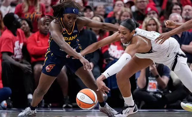 Indiana Fever guard Raven Johnson, left, and Las Vegas Aces center A'ja Wilson vie for a loose ball during the first half in Game 2 of a WNBA basketball first-round playoff series in Indianapolis, Tuesday, Sept. 29, 2026. (AP Photo/Michael Conroy)