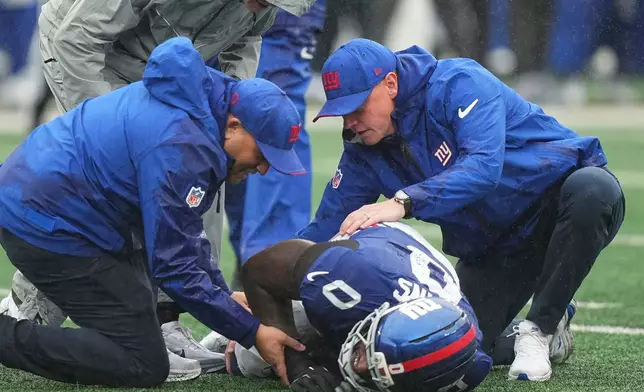 New York Giants linebacker Brian Burns (0) is assisted by the team's medical staff after being injured during the second half of an NFL football game against the Tennessee Titans in East Rutherford, N.J., Sunday, Sept. 27, 2026. (AP Photo/Frank Franklin II)