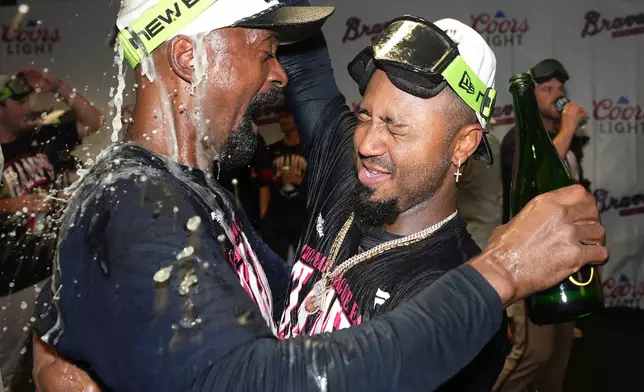 Atlanta Braves' Ozzie Albies, right, celebrates in the visitors' clubhouse with hitting coach Darnell Coles, left, after a baseball game against the Houston Astros as the Braves clinched the NL East title, Sunday, Sept. 20, 2026, in Houston. (AP Photo/Karen Warren)
