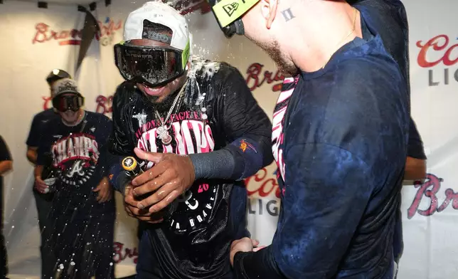 Atlanta Braves' Ozzie Albies, front left, celebrates in the visitors' clubhouse with DaShawn Keirsey Jr., right, after a baseball game against the Houston Astros as the Braves cinched the NL East title, Sunday, Sept. 20, 2026, in Houston. (AP Photo/Karen Warren)