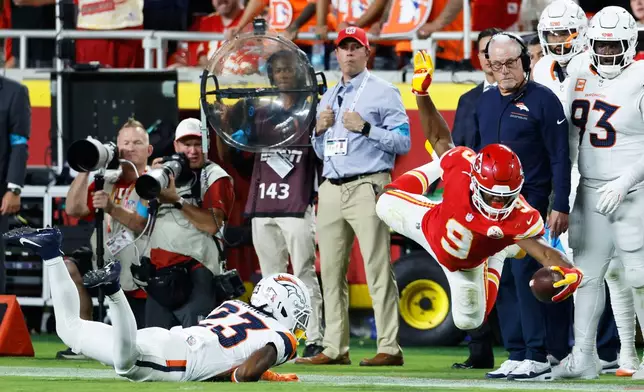 Kansas City Chiefs running back Kenneth Walker III (9) catches a pass and dives for a first down against Denver Broncos cornerback Jahdae Barron (23) during the first half of an NFL football game Monday, Sept. 14, 2026, in Kansas City, Mo. (AP Photo/Colin E. Braley)