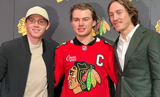 In this photo taken with a smartphono, Chicago Blackhawks players, from left, Patrick Kane, Connor Bedard and Tyler Bertuzzi pose during a news conference introducing Bedard as the new captain of the NHL hockey club, Tuesday, Sept. 15, 2026, in Chicago. (AP Photo/Jay Cohen)