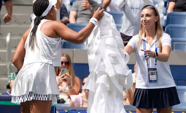 Naomi Osaka, of Japan, hands off her arrival outfit ahead of a match against Katerina Siniakova, of the Czech Republic, during the second round of the U.S. Open tennis championships Thursday, Sept. 3, 2026, in New York. (AP Photo/Seth Wenig)