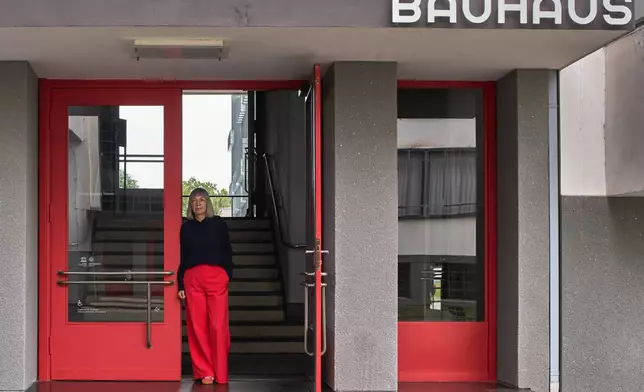 Barbara Steiner, the director of the Bauhaus Dessau Foundation poses for a photo at the entrance of the main building of the former design school, which was called an "aberration of modernism" by Germany's far-right Alternative for Germany party, in Dessau, Germany, Aug. 17, 2026. (AP Photo/Markus Schreiber)