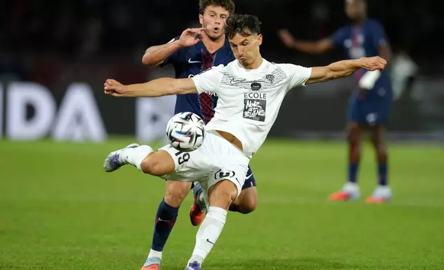 FILE - Angers' Esteban Lepaul kicks the ball, chased by PSG's Joao Neves during the League One soccer match Paris Saint-Germain against Angers at the Parc des Princes stadium, Friday, Aug. 22, 2025 in Paris. (AP Photo/Aurelien Morissard, File)