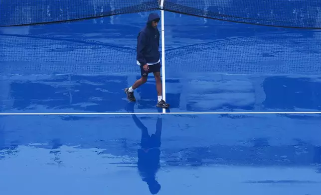 A crew member walks across the court at Grandstand stadium during a rain delay at the U.S. Open tennis championships Tuesday, Sept. 1, 2026, in New York. (AP Photo/Kirsty Wigglesworth)