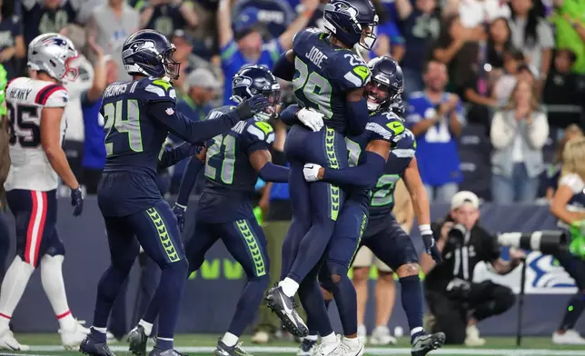 Seattle Seahawks cornerback Josh Jobe, top right, is lifted by safety Julian Love as they celebrate Jobe's interception in the end zone during the second half of an NFL football game against the New England Patriots, Wednesday, Sept. 9, 2026, in Seattle. (AP Photo/Lindsey Wasson)