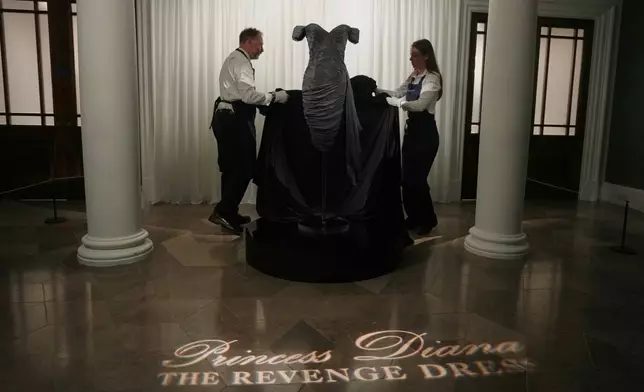 A dress worn by the late Princess Diana and known as the ''Revenge Dress'', designed by Christina Stambolian, is unveiled by staff at Sotheby’s auction house in London, Friday, Sept. 18, 2026, ahead of its Dec. 9 auction in New York, where it is estimated to sell for US$150,000-300,000. (AP Photo/Alastair Grant)