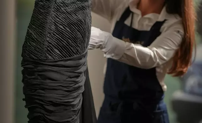 A dress worn by the late Princess Diana and known as the ''Revenge Dress'', designed by Christina Stambolian, is unveiled by staff at Sotheby’s auction house in London, Friday, Sept. 18, 2026, ahead of its Dec. 9 auction in New York, where it is estimated to sell for US$150,000-300,000. (AP Photo/Alastair Grant)