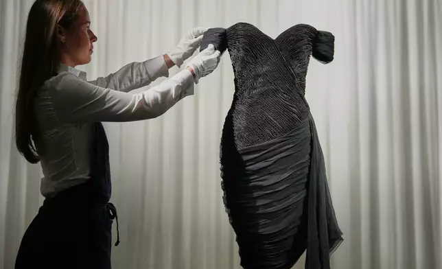 A dress worn by the late Princess Diana and known as the ''Revenge Dress'', designed by Christina Stambolian, is unveiled by staff at Sotheby’s auction house in London, Friday, Sept. 18, 2026, ahead of its Dec. 9 auction in New York, where it is estimated to sell for US$150,000-300,000. (AP Photo/Alastair Grant)
