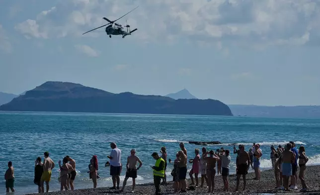 Tourists from nearby hotels watch a military helicopter fly overhead during Medusa 15, a multinational military exercise led by Greece and Egypt, at Maleme on the Greek island of Crete, Friday, Sept. 18, 2026. (AP Photo/Thanassis Stavrakis)