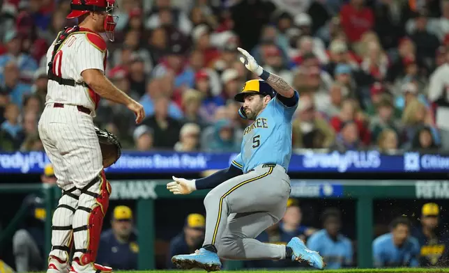 Milwaukee Brewers' Garrett Mitchell (5) scores past Philadelphia Phillies catcher J.T. Realmuto during the fourth inning of a baseball game, Tuesday, Sept. 22, 2026, in Philadelphia. (AP Photo/Matt Rourke)