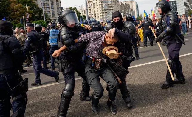 A demonstrator is detained following scuffles with riot police during a farmers' protest in Bucharest, Romania, Tuesday, Sept. 15, 2026. (AP Photo/Andreea Alexandru)