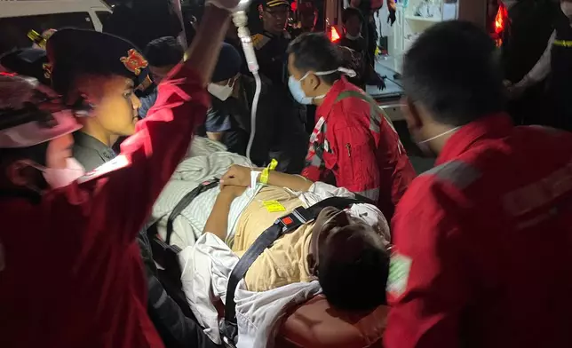 In this photo taken with a smartphone, rescuers wheels a survivor of a sinking ferry on a stretcher upon arrival at a port in Banjarmasin, South Kalimantan, Indonesia, Sunday, Sept. 13, 2026. (AP Photo/Iman Satria)