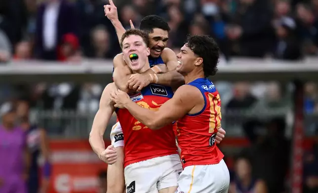 Brisbane Lions players Logan Morris, center, Charlie Cameron, rear, and Cam Rayner celebrate their win over the Fremantle Dockers in the Australian Football League grand final in Melbourne, Australia Saturday, Sept. 26, 2026. (Joel Carrett/AAP Image via AP)