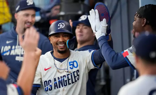 Los Angeles Dodgers' Mookie Betts is congratulated by teammates in the dugout after scoring on a double by Kyle Tucker during the first inning of a baseball game against the San Francisco Giants, Saturday, Sept. 19, 2026, in Los Angeles. (AP Photo/Mark J. Terrill)