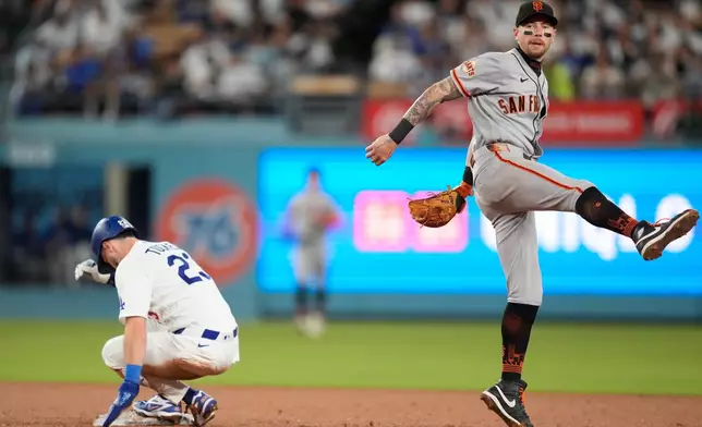 San Francisco Giants shortstop Christian Koss, right, throws out Los Angeles Dodgers' Teoscar Hernández at first after Kyle Tucker, left, was forced out at second during the fourth inning of a baseball game Friday, Sept. 18, 2026, in Los Angeles. (AP Photo/Mark J. Terrill)
