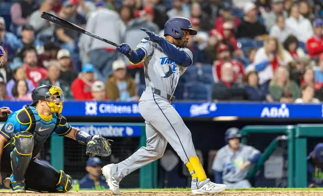 Tampa Bay Rays' Cedric Mullins, right, follows through on a single during the ninth inning of a baseball game against the Philadelphia Phillies, Friday, Sept. 25, 2026, in Philadelphia. (AP Photo/Laurence Kesterson)