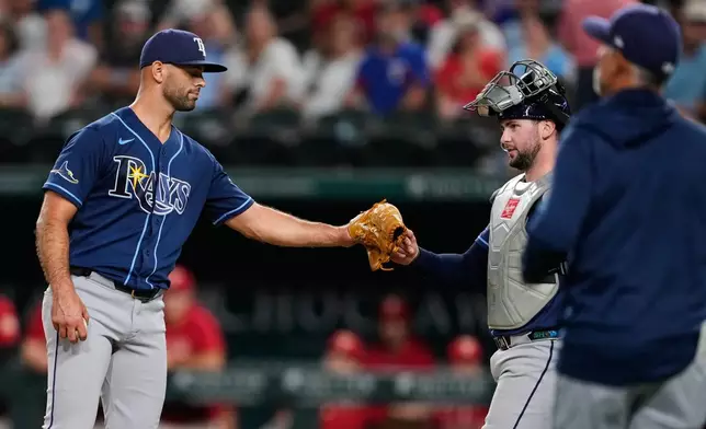 Tampa Bay Rays pitcher Nick Martinez, left, bumps fist with catcher Liam Hicks, right rear, as manager Kevin Cash, right front, walks out to make a pitching change during the seventh inning of a baseball game against the Texas Rangers Friday, Sept. 4, 2026, in Arlington, Texas. (AP Photo/Tony Gutierrez)
