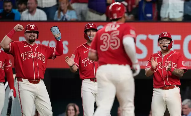 Texas Rangers' Jake Burger, left rear, Evan Carter and Cody Freeman, right rear, celebrate as Elias Díaz (35) approaches the plate after hitting a grand slam that scored the trio during the seventh inning of a baseball game against the Tampa Bay Rays Friday, Sept. 4, 2026, in Arlington, Texas. (AP Photo/Tony Gutierrez)