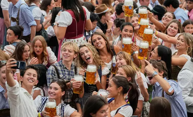 Young people cheer after the opening of the 191st Oktoberfest beer festival in Munich, Germany, Saturday, Sept.19, 2026. (AP Photo/Matthias Schrader)