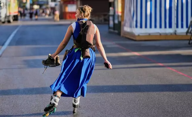 A waitresses skates to work prior to the opening of the 191st Oktoberfest beer festival in Munich, Germany, Saturday, Sept.19, 2026. (AP Photo/Matthias Schrader)