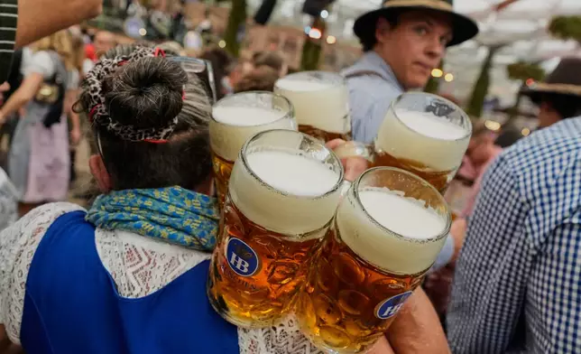 A waitress carries beer mugs after the opening of the 191st Oktoberfest beer festival in Munich, Germany, Saturday, Sept.19, 2026. (AP Photo/Matthias Schrader)